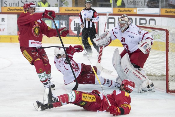 Langnaus Thomas Nuessli, links, und Chris DiDomenico, unten, kaempfen um den Puck, gegen Lausannes Goalie Cristobal Huet, rechts, und Lausannes John Gobbi, Mitte, waehrend dem Eishockey National Leagu ...