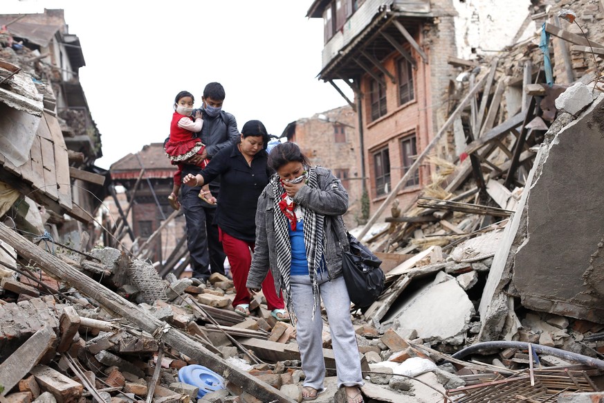 epa04725724 A family walks amid the rubble in Bhaktapur in the aftermath of the earthquake that struck over the weekend, Nepal, 29 April 2015. The number of people killed in the earthquake in Nepal pa ...
