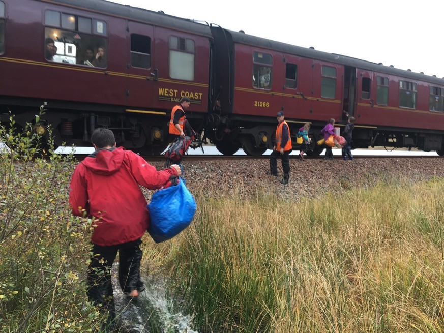 In this photo taken on Friday, Oct. 13, 2017, children run towards a train near Loch Eilt in the Scottish Highlands. As if by magic, the Hogwarts Express has come to the rescue of a stranded family in ...