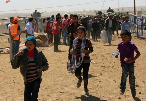 Flüchtlinge aus Kobani überqueren die türkische Grenze.