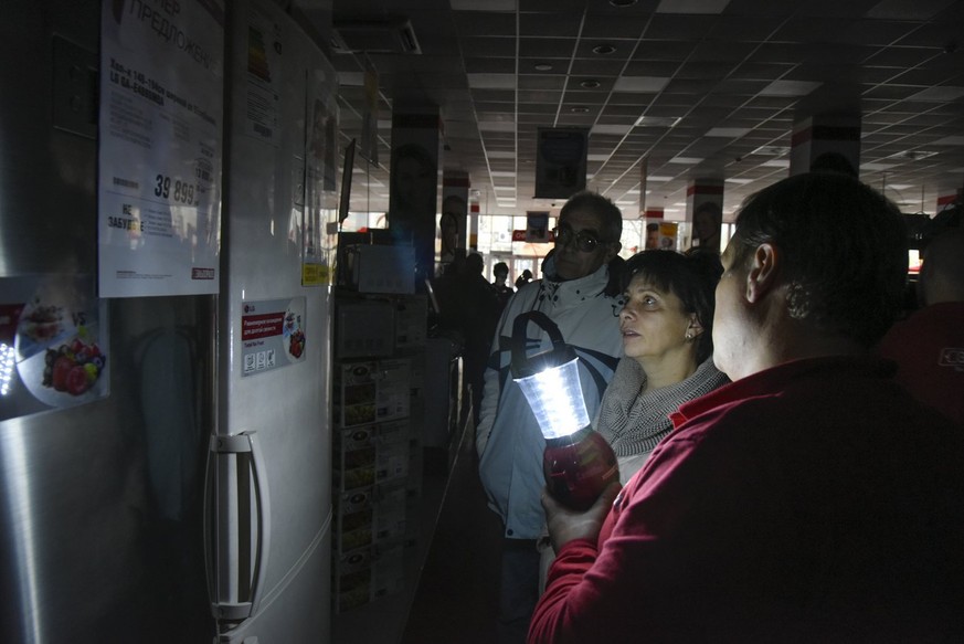 An electronics store employee uses a lamp to show items to potential customers after a power failure, in Simferopol, Crimea, Sunday, Nov. 22, 2015. Russia&#039;s Energy Ministry says nearly 2 million  ...