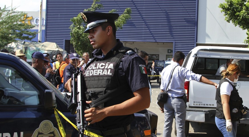 Police and forensics secure the area where six people lie dead, two of them covered with cardboard at right, in Acapulco, Mexico, Wednesday, Jan. 4, 2017. According to a city government spokesman, uni ...