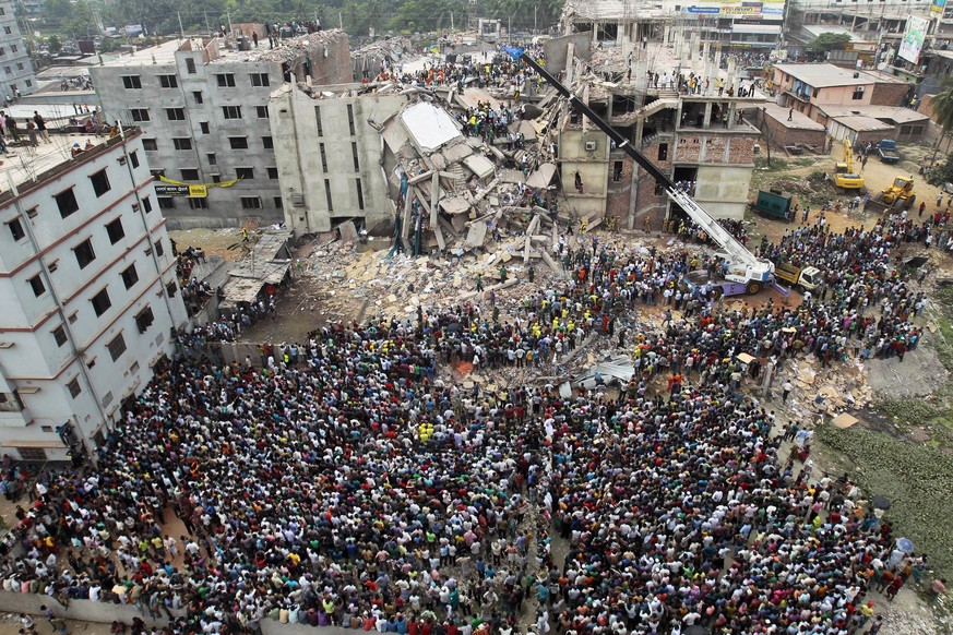 FILE - In this April 25, 2013, file photo, Bangladeshi people gather as rescuers search for survivors and victims after the Rana Plaza building collapsed which housed five garment factories in Savar,  ...