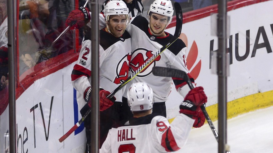 New Jersey Devils defencsman John Moore, left, celebrates his game winning goal against the Ottawa Senators with teammates Nico Hischier, right, and Taylor Hall in overtime in an NHL hockey game, Thur ...