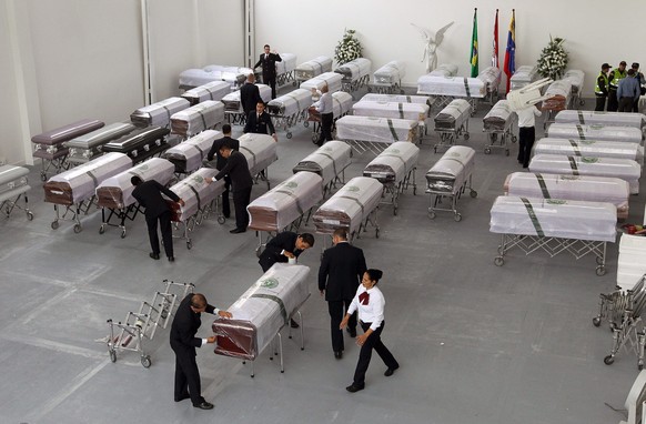 epa05656788 Workers of the funeral home San Vicente move the coffins of the Brazilian soccer team Chapecoense to be loaded for repatriation in Antioquia, Colombia, 02 December 2016. Repatriation of th ...