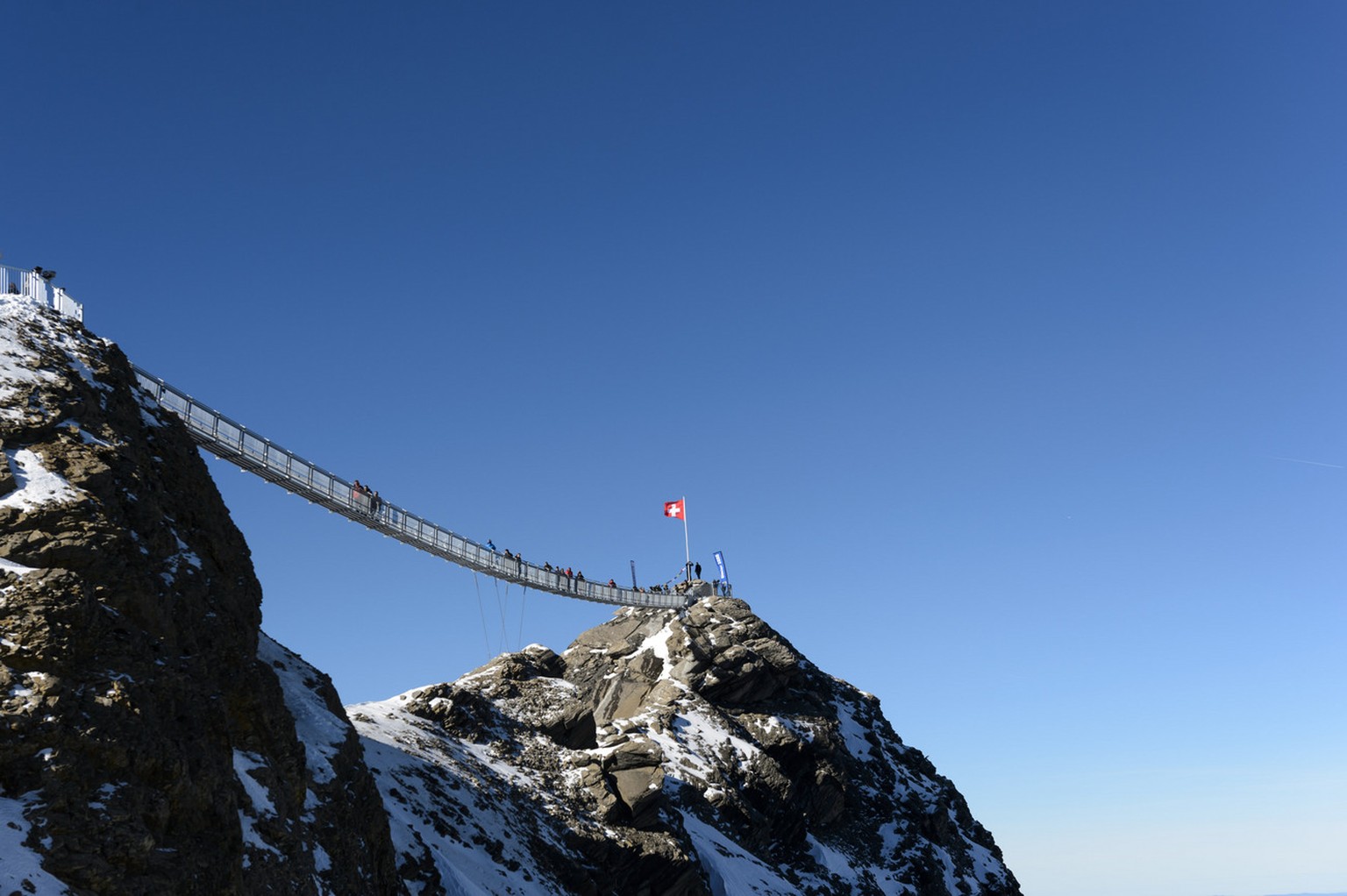 People walk on the bridge during the inauguration of the Peak Walk, the first and only suspension bridge to connect two mountain peaks, at the Glacier 3000 in Les Diablerets, Switzerland, Friday, 24 O ...