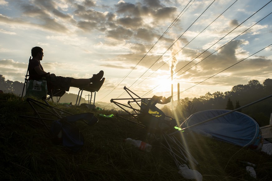 Ein Mann geniesst den Sonnenaufgang ueber der Zeltstadt am Openair St. Gallen, aufgenommen am Sonntag, 28. Juni 2015 in St. Gallen. (KEYSTONE/Ennio Leanza)