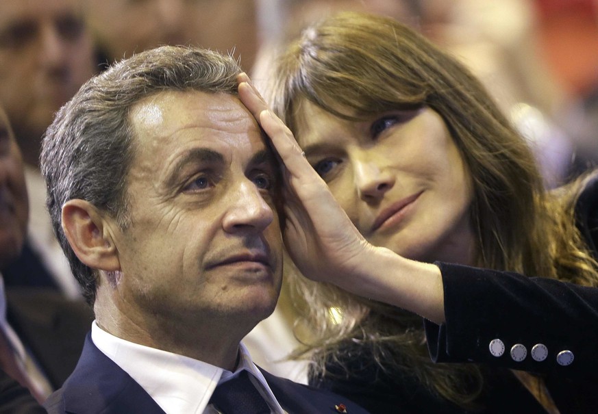 FILE - In this Thursday, Oct. 27, 2016 file picture, Carla Bruni-Sarkozy caresses the brow of her husband, the former French President and candidate for France&#039;s conservative presidential primary ...