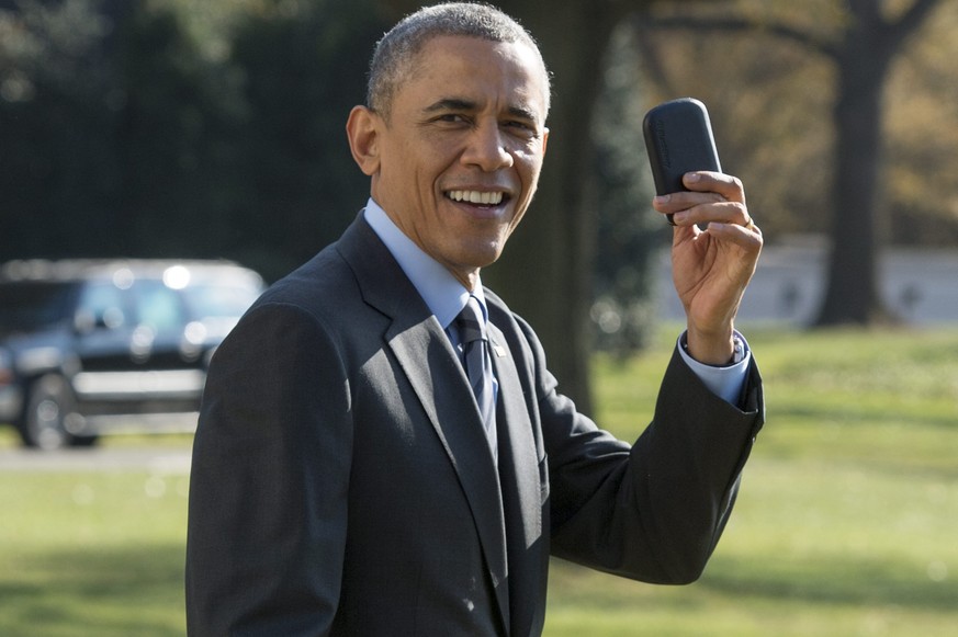 epa04498424 US President Barack Obama shows members of the media his BlackBerry device that he forgot and needed to walk back into the White House to retrieve after boarding Marine One, before departi ...