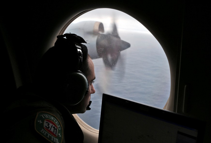 Flight officer Rayan Gharazeddine looks out of a Royal Australian Air Force (RAAF) AP-3C Orion as it flies over the southern Indian Ocean during the search for missing Malaysian Airlines flight MH370  ...