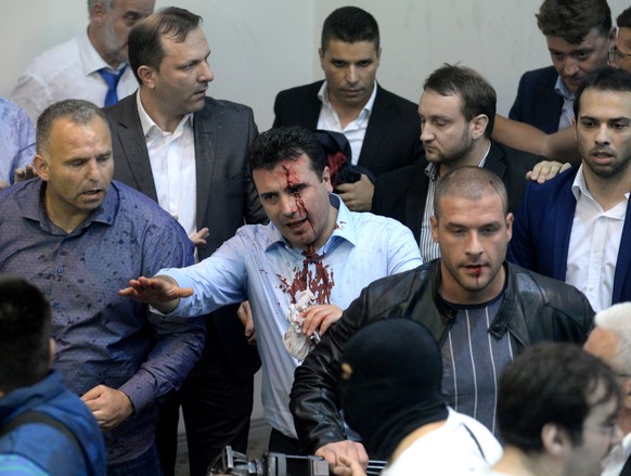 epa05931625 Zoran Zaev (C), the leader of Social Democratic Union of Macedonia with blood on his face tries to leave the Parliament after protestors attacked him after they stormed the Macedonian Parl ...