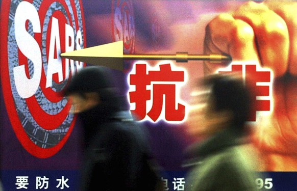 FILE - In this Dec. 18, 2003, file photo, people walk past a local government &#039;s anti-SARS advertisement in Shanghai, China. Nearly two decades after the disastrously-handled SARS epidemic, China ...