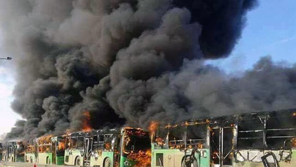 In this photo released by the Syrian official news agency SANA, smoke rises in green government buses, in Idlib province, Syria, Sunday, Dec. 18, 2016. Activists said, militants have burned at least f ...