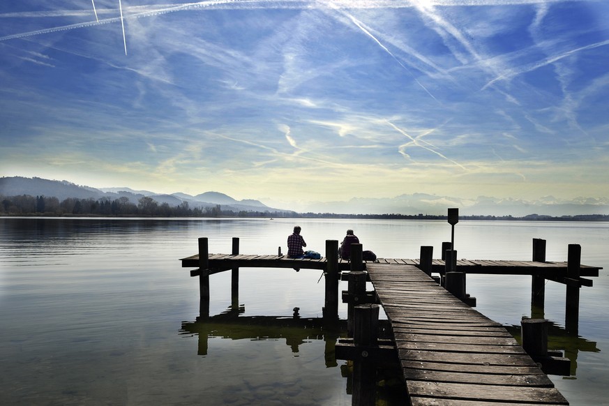 Zwei Frauen geniessen die milde Fruehlingssonne auf einem Steg am Pfaeffikersee bei Pfaeffikon (ZH), am Donnerstag, 30. Maerz 2017. (KEYSTONE/Walter Bieri)