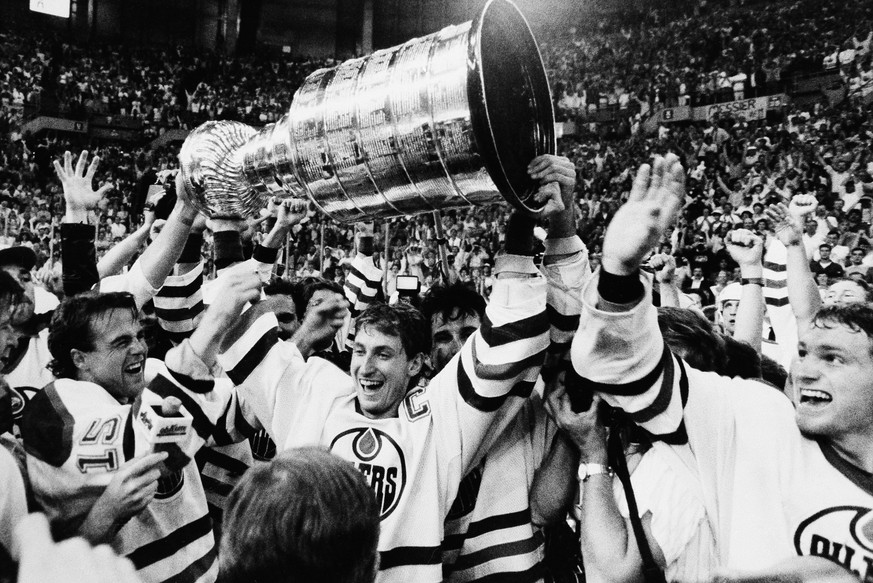 Edmonton Oilers team caption Wayne Gretzky is flanked by teammates as he skates with the Stanley Cup following their 3-1 victory over the Philadelphia Flyers in the seventh game of the Stanley Cup fin ...