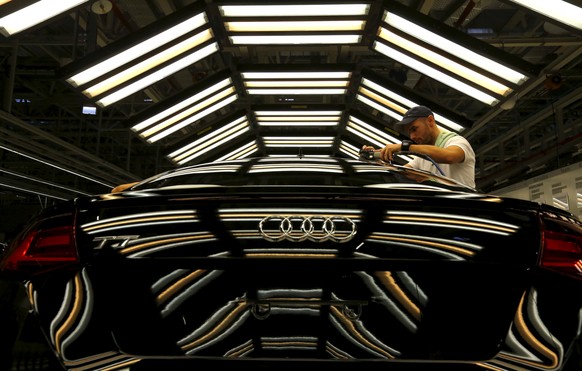 A worker stands next to a car on the assembly line as serial production of the new Audi TT roadster starts at the Audi plant in Gyor, west of Budapest November 5, 2014. REUTERS/Laszlo Balogh/File Phot ...