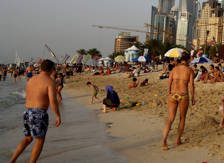 In this Saturday, April 19, 2014 photo, people enjoy the beach in Dubai, United Arab Emirates. The ribbon of beach nestled along the towering skyscrapers rising from Dubai’s man-made marina district i ...