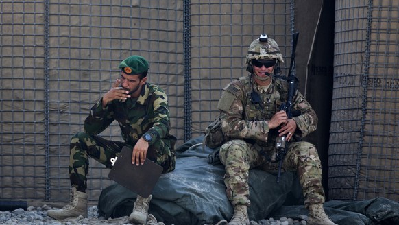 FILE - In this Wednesday, Aug. 5, 2015 file photo, an Afghan National Army soldier, left, smokes as a U.S. Army soldier from Charlie Company, 2-14 Infantry Regiment, 2nd Brigade, 10th Mountain Divisio ...