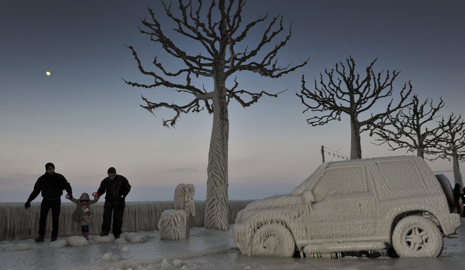 Some people walk along an ice covered car on the iced waterside promenade at the Lake Geneva in Versoix, Switzerland, Sunday, February 5, 2012. A cold spell has reached Europe with temperatures plumme ...