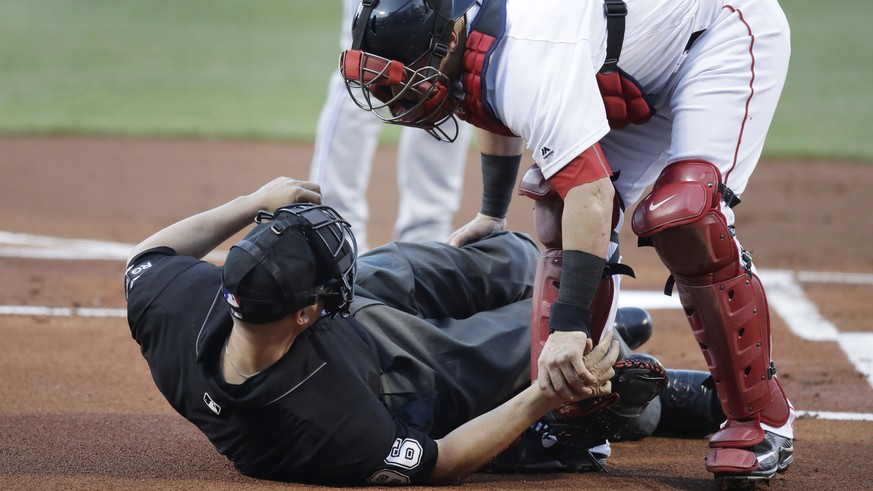 Boston Red Sox catcher Christian Vazquez aids home plate umpire Chris Segal after he was accidentally hit on the head by Toronto Blue Jays&#039; Josh Donaldson&#039;s bat during the first inning of a  ...