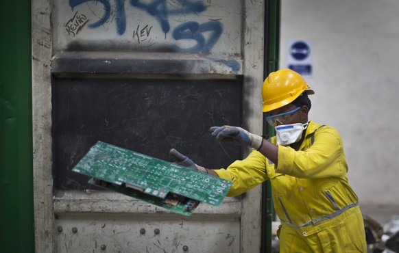 In this photo taken Monday, Aug. 18, 2014, a worker sorts printed circuit boards from a container full of electronic waste that was collected from a Nairobi slum and brought in for recycling, at the E ...