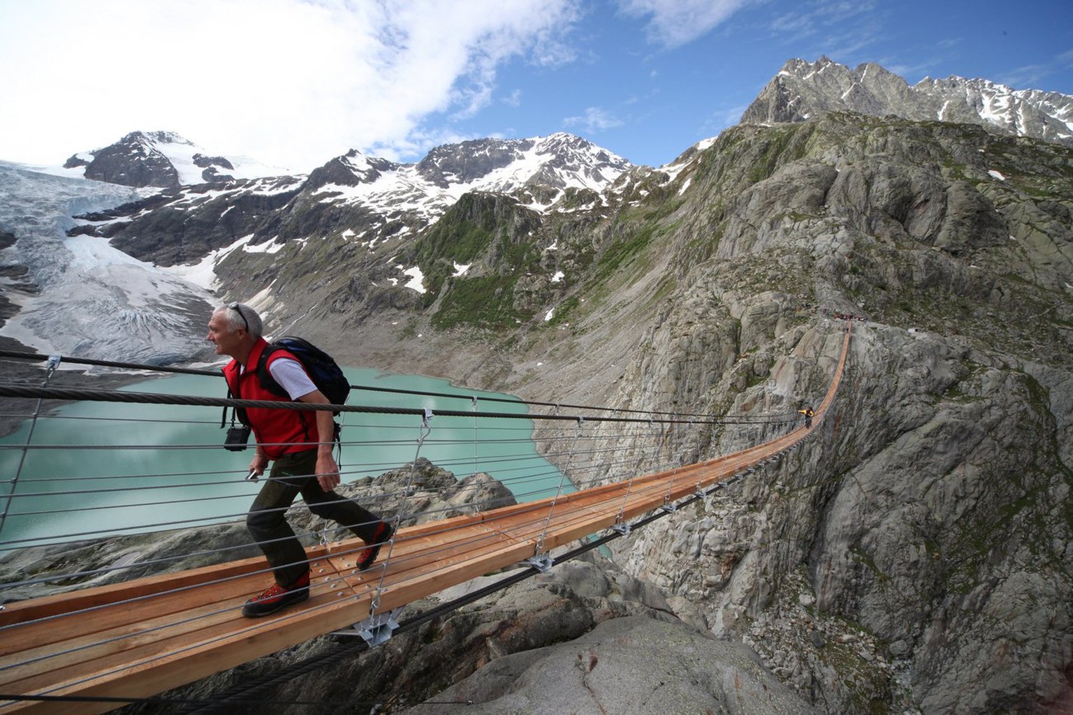 Ein Wanderer marscherit ueber die neue Triftbruecke unterhalb des Triftsee und des Triftgletscher im Sustengebiet am Freitag 12. Juni 2009. Die Bruecke wurde heute eroeffnet und ist ab sofort fuer die ...