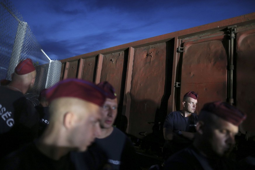 Ungarische Soldaten vor einem Zugwagen, der Zaunmaterial an die Grenze fugt.