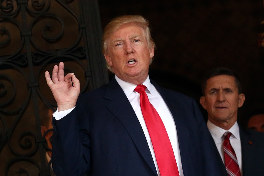 U.S. President-elect Donald Trump talks to members of the media as retired U.S. Army Lieutenant General Michael Flynn stands next to him at Mar-a-Lago estate in Palm Beach, Florida, U.S., December 21, ...