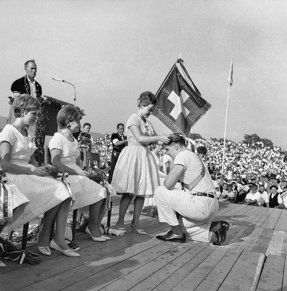 A young woman places a garland on Karl Meli&#039;s head, the new wrestling champion, at the Swiss Wrestling and Alpine Festival in Aarau, canton of Aargau, Switzerland, on August 16, 1964. (KEYSTONE/S ...