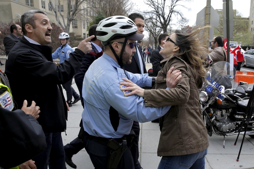 Ein Leibwächter aus Erdogans Sicherheitstrupp droht einer Demonstrantin. Ein US-Polizist hindert sie daran, auf den Security-Mann loszugehen.&nbsp;