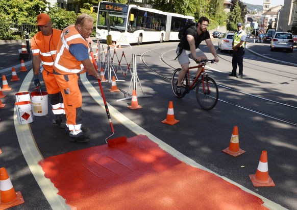 Ein potentiell gefaehrlicher Veloweg wird von Arbeitern rot markiert, am Dienstag, 1. Juli 2014, an der Leonhardstrasse in Zuerich. Grund der Massnahme ist die vorgesehene Verbesserung der Infrastrukt ...