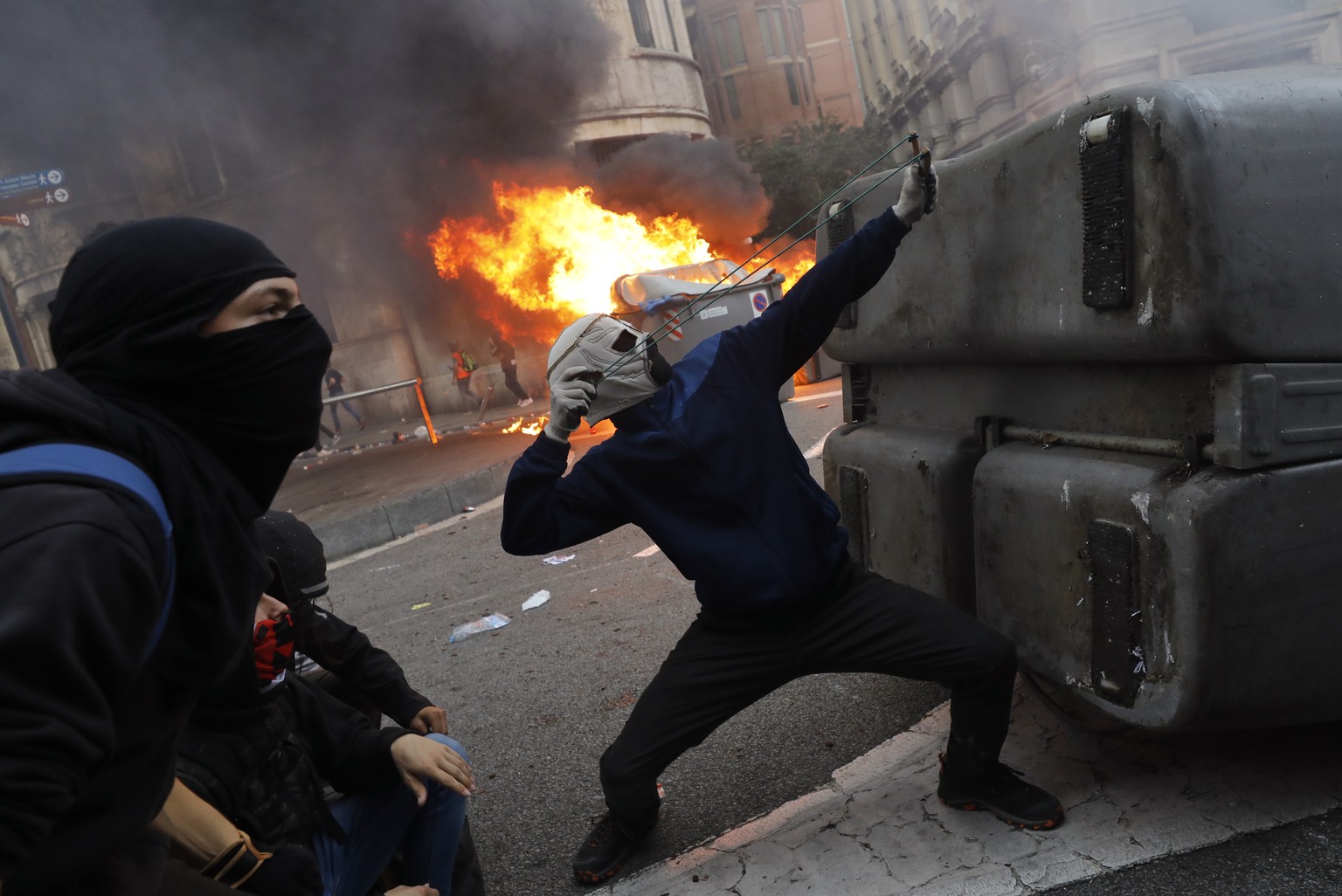 A protestors uses a sling during clashes with police in Barcelona, Spain, Friday, Oct. 18, 2019.The Catalan regional capital is bracing for a fifth day of protests over the conviction of a dozen Catal ...