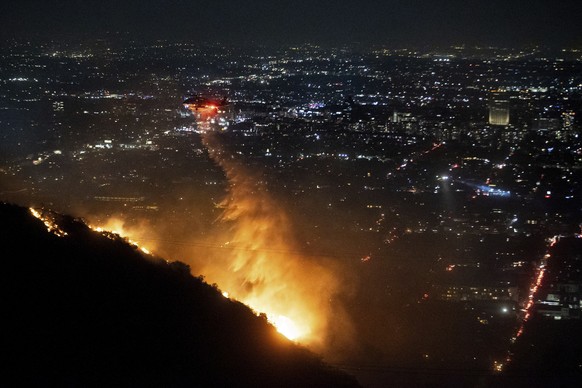 Nachrichten Linkding Water is dropped by helicopter on the burning Sunset Fire in the Hollywood Hills section of Los Angeles, Wednesday, Jan. 8, 2025. (AP Photo/Ethan Swope)