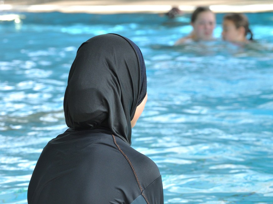ARCHIV - Eine muslimische Schülerin sitzt am 23.06.2009 in einem Ganzkörper-Badeanzug (Burkini) am Rande eines Schwimmbeckens. Zwei muslimische Eltern aus Basel wehren sich vor dem Europäischen Mensch ...