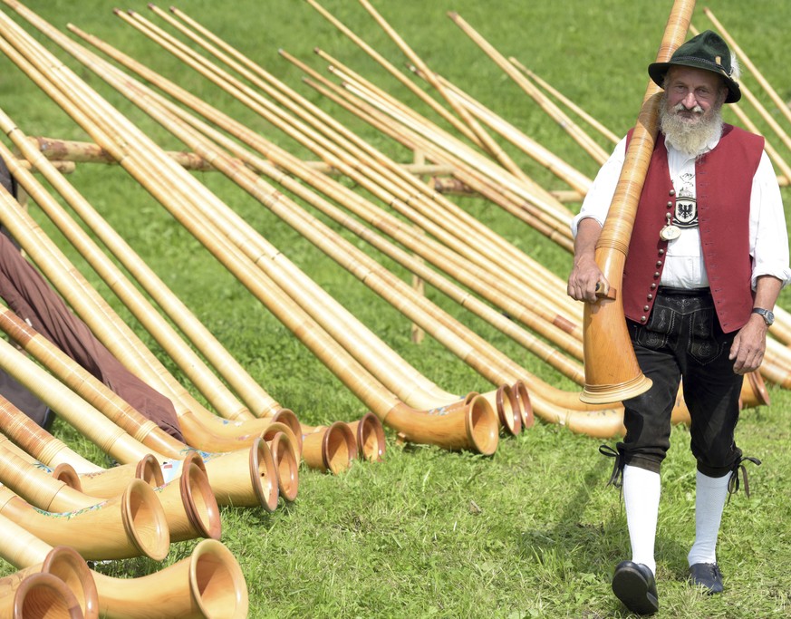 A musician carries his alphorn past others during a meeting of alphorn musicians in Engetried near Markt Rettenbach, southern Germany, Sunday, Aug. 27, 2017. About 300 musician participated at the mee ...