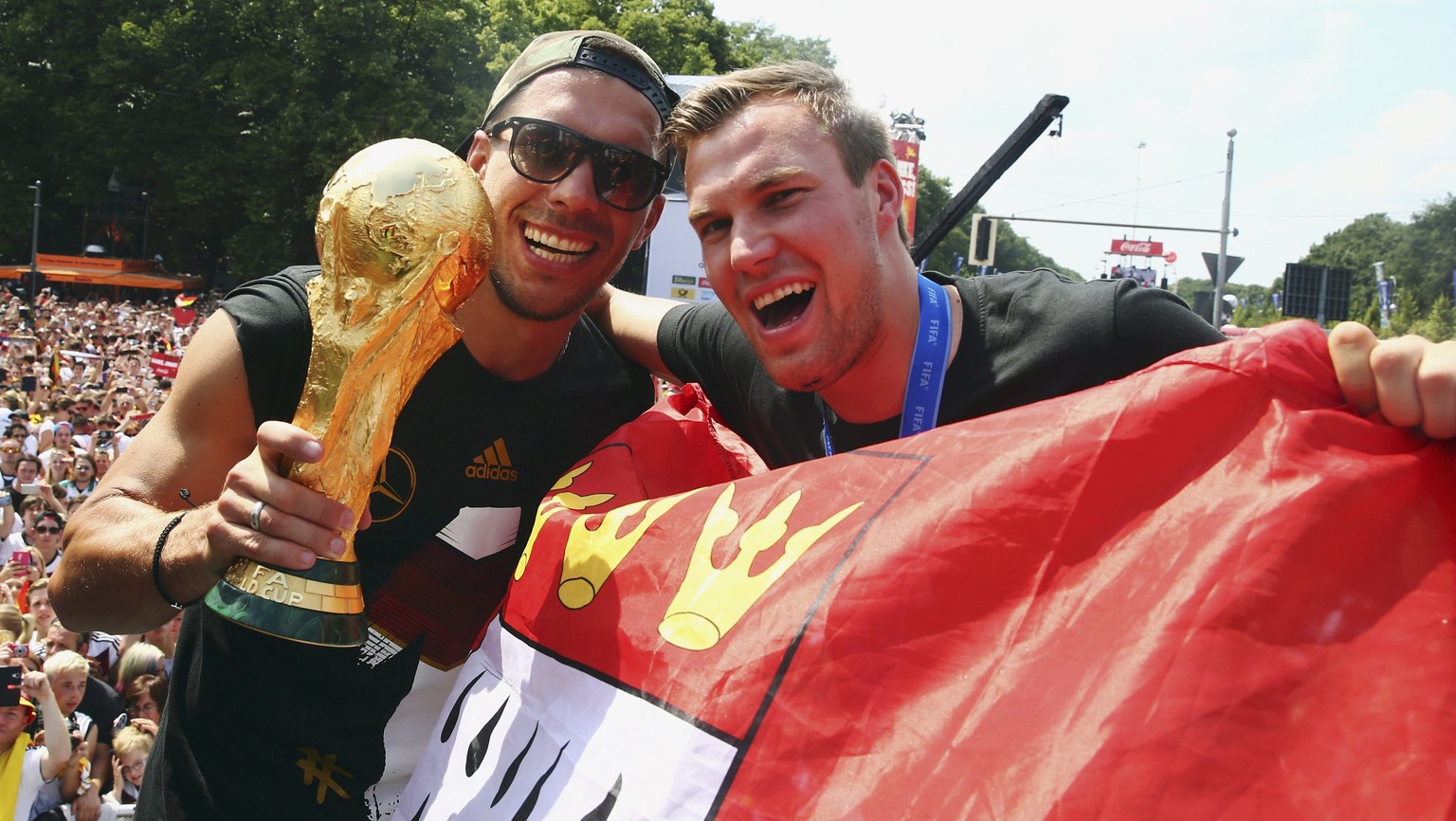 Germany&#039;s Lukas Podolski (L) and Kevin Grosskreutz pose with the World Cup trophy during celebrations to mark the team&#039;s 2014 Brazil World Cup victory, at a &#039;fan mile&#039; public viewi ...