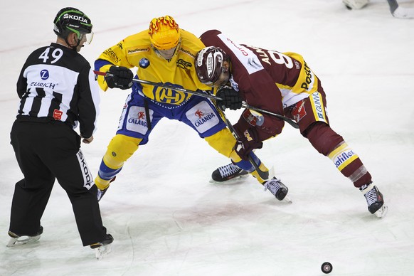 Davos&#039; center Perttu Lindgren, of Finland, left, vies for the puck with Geneve-Servette&#039;s forward Cody Almond, right, past Linesmen Roman Kaderli #49, during the game of National League A (N ...