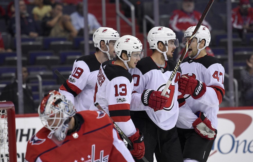 New Jersey Devils center Nico Hischier (13), of Switzerland, celebrates his goal with John Quenneville (47), Marcus Johansson, second from right, and Drew Stafford (18) as Washington Capitals goalie B ...
