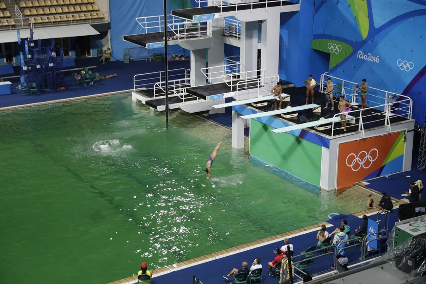 The water of the diving pool appears a murky green, in stark contrast to the pool&#039;s previous day&#039;s color and also that of the clear blue water in the second pool for water polo at the venue  ...