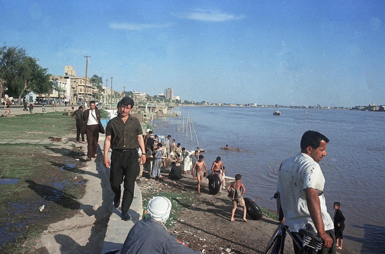 Children play in muddy water of Tigris in Iraq as adults stroll in afternoon sun, May 31, 1967. (AP Photo)