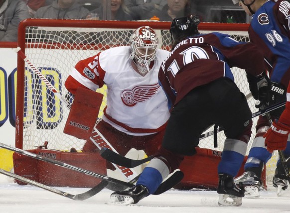 Detroit Red Wings goalie Jimmy Howard, back, stops a shot by Colorado Avalanche right wing Sven Andrighetto, of Switzerland, during the first period of an NHL hockey game Wednesday, March 15, 2017, in ...