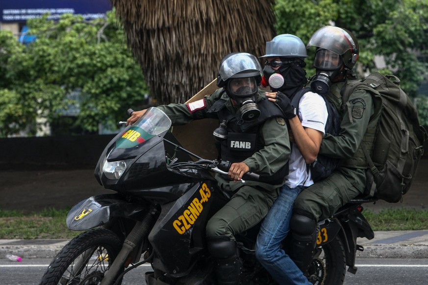 epa05962495 Members of Venezuelan Bolivarina Guard arrest an opposition sympathizer during a protest against the Government in Caracas, Venezuela, 13 May 2017. Policemen broke up the protest with tear ...