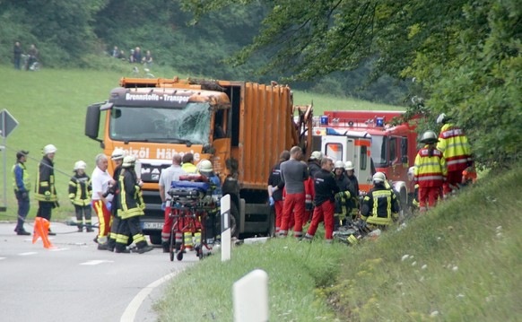 Feuerwehrkraefte arbeiten am 11.08.2017 auf einer Strasse bei Nagold (Baden-Wuerttemberg) an einer Unfallstelle, an der ein Muellwagen auf ein Auto gekippt war. Nach ersten Angaben der Polizei sind be ...