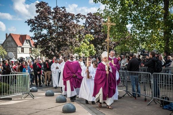 epa05566787 Archibishop of Rouen Dominique Lebrun holds a cross in front of a procession before a Catholic mass celebrated for the re-opening of the Saint Etienne church in Saint-Etienne-du-Rouvray, n ...