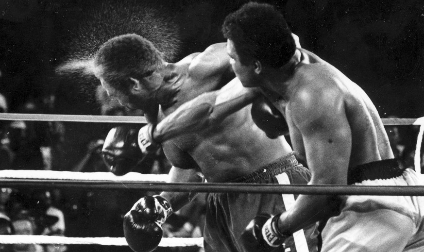 FILE - This is a Oct. 30, 1974 file photo perspiration flies from the head of George Foreman as he takes a right from challenger Muhammad Ali in the seventh round in the match dubbed Rumble in the Jun ...