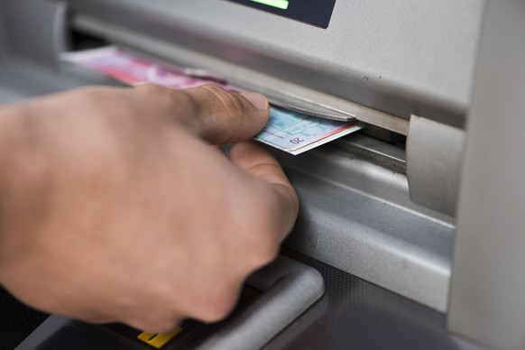 ZUM THEMA GELD STELLEN WIR IHNEN HEUTE, DONNERSTAG, 1. OKTOBER 2015, FOLGENDES NEUES BILDMATERIAL ZUR VERFUEGUNG --- A person takes twenty Swiss franc bills out of a cash dispenser while withdrawing m ...