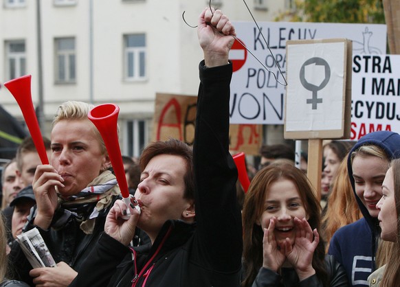 Polish women and some male supporters blow horns while raising a hanger, the symbol of illegal abortion, during a nationwide strike and demonstration to protest a legislative proposal for a total ban  ...