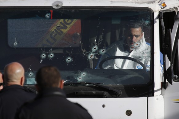 epa05705067 A forensic investigator of the Israeli police examines the cockpit of a truck with bullet holes in its windshield after a truck ramming attack on the Armon Hanatziv promenade in Jerusalem, ...