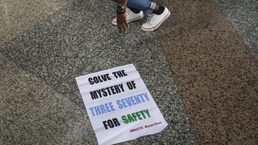 epa05657554 Malaysian Grace Subathirai Nathan (top, obscured), whose mother Anne Daisy was on board missing flight MH370, leaves a banner on the ground during a press conference at Kuala Lumpur Intern ...