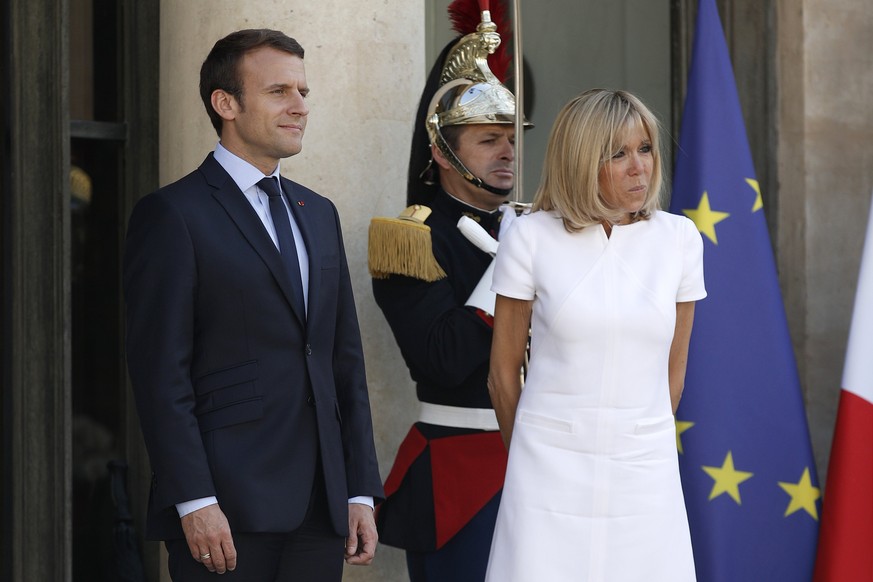 epa06017097 French President Emmanuel Macron (L) and his wife Brigitte Macron (C) look on as the President of Guatemala, Jimmy Morales (unseen), leaves the Elysee Palace following their meeting in Par ...